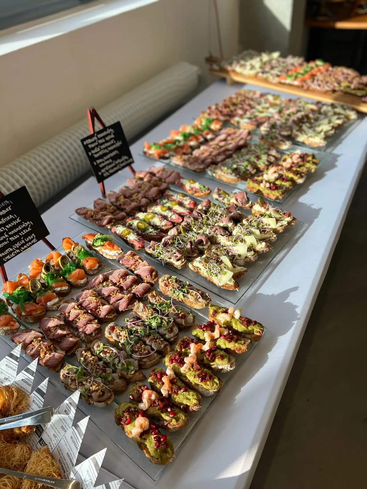 Dlouhý světlý rautový stůl plný pintxos
